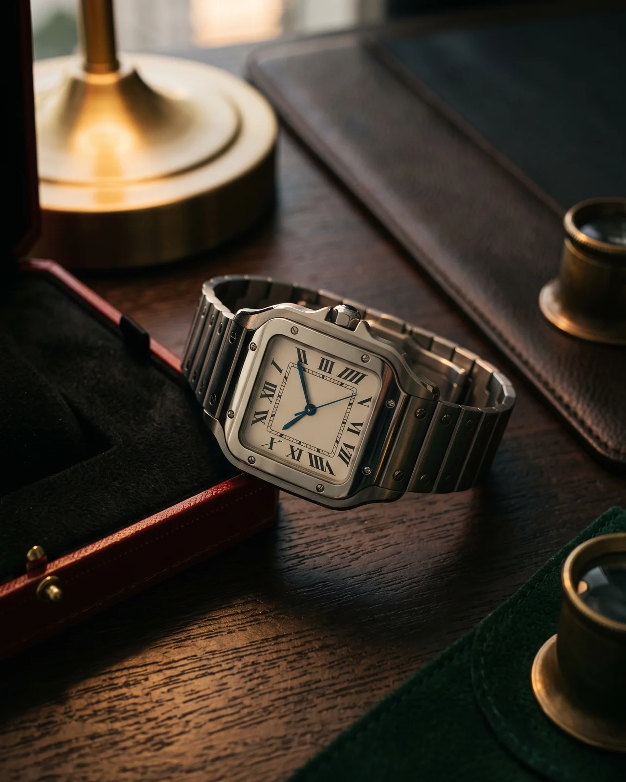 A square steel Cartier Santos bezel with its eight exposed screws, seen from above on dark leather so the screw slots are readable.