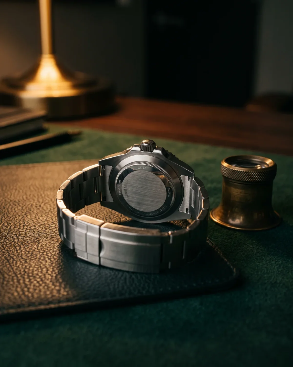 An Omega warranty card and a Master Chronometer certificate card laid beside a closed watch box and a steel dive watch on a dark desk.