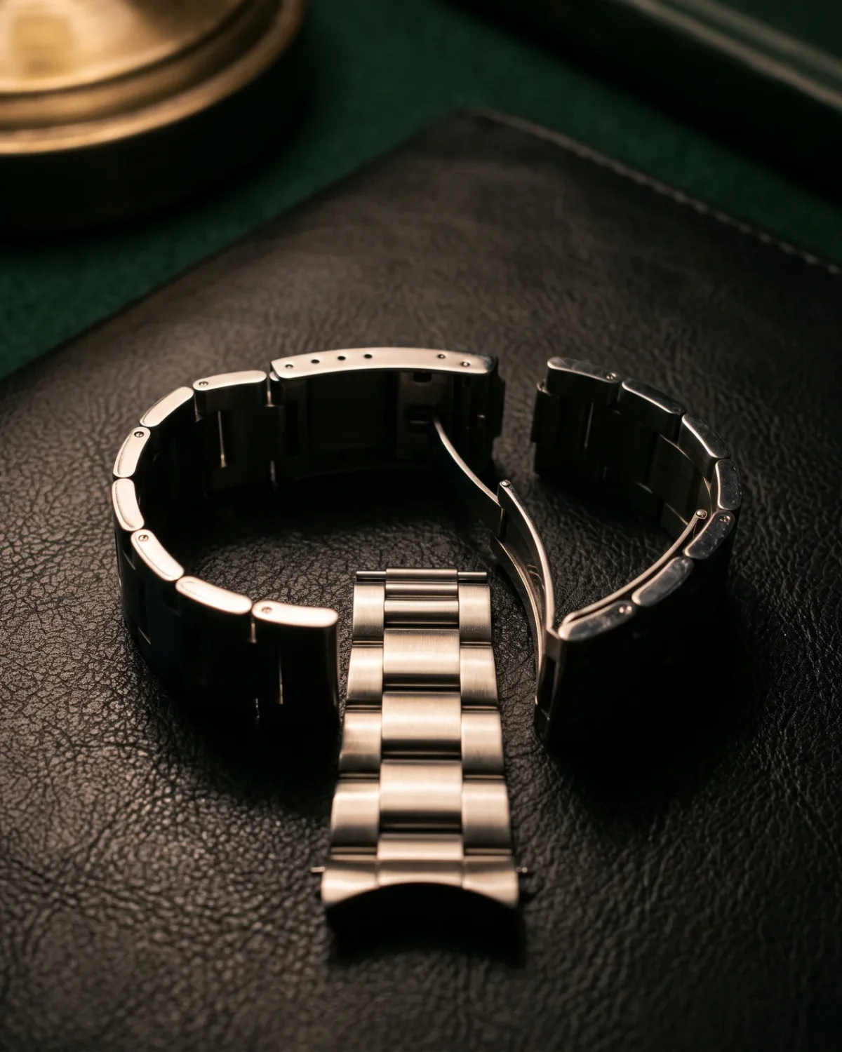 A jeweller's loupe resting on an open notebook beside a steel watch, the tools of reading a watch closely.