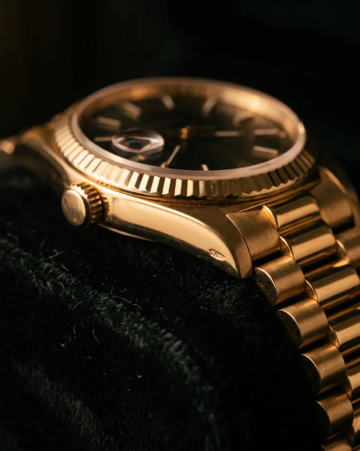 A folded paper watch certificate, a sealed archive envelope, and a leather strap with a gold buckle arranged beside a closed wooden watch box on a dark desk.