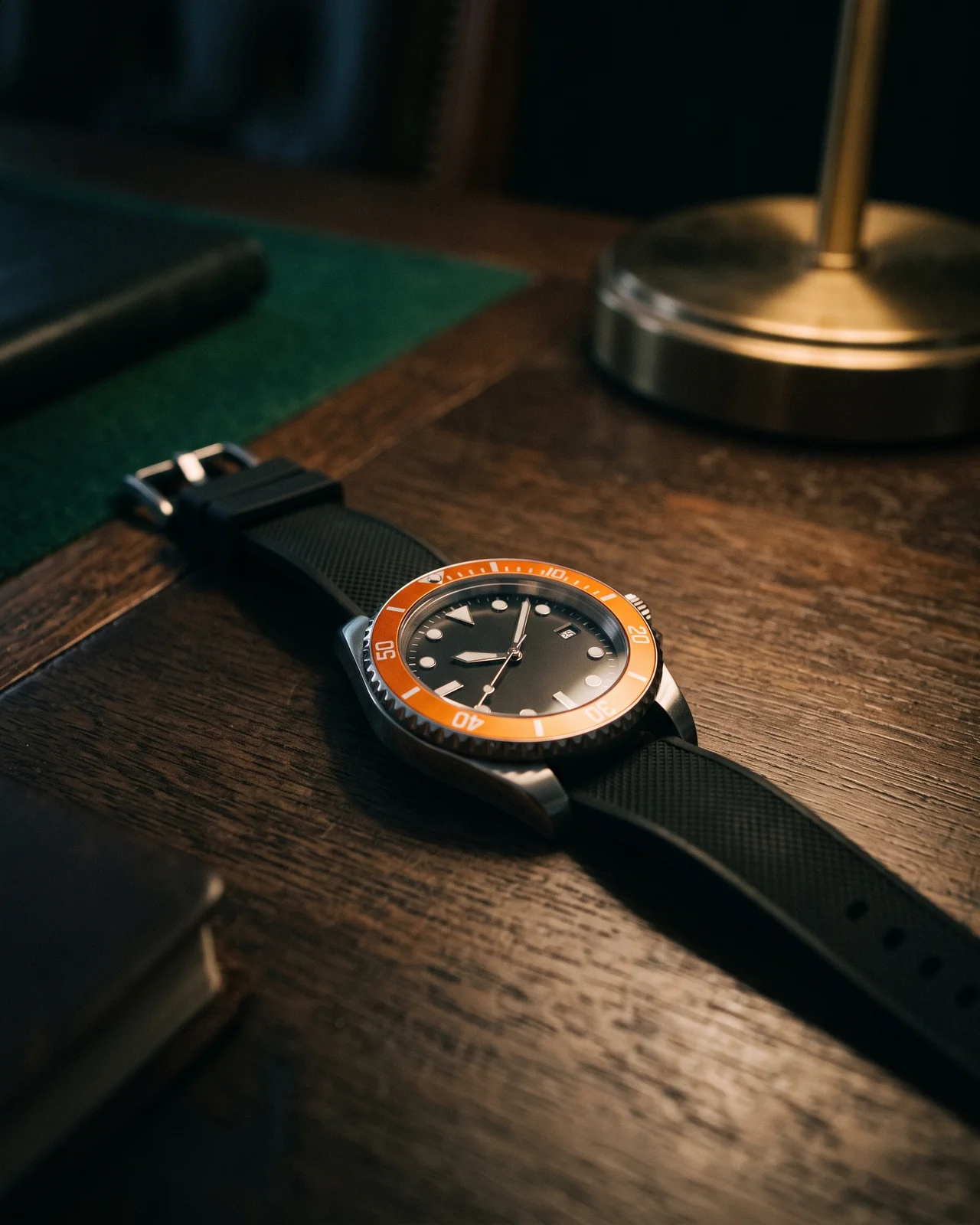 A steel Omega Planet Ocean from above, black ceramic bezel and orange-tipped seconds hand sharp against dark leather, helium valve visible at ten o'clock.