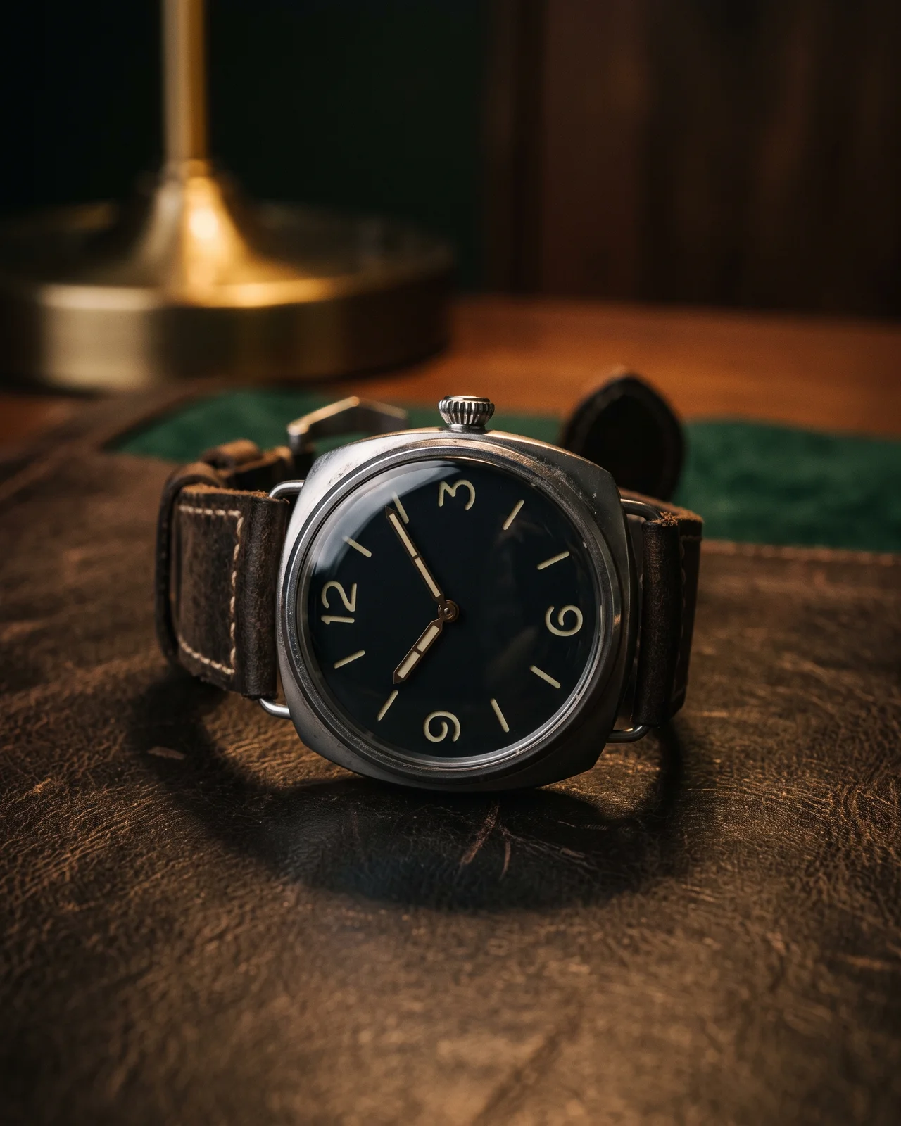 The wire lugs and conical crown of a steel Panerai Radiomir on dark leather, the polished cushion case catching one light.