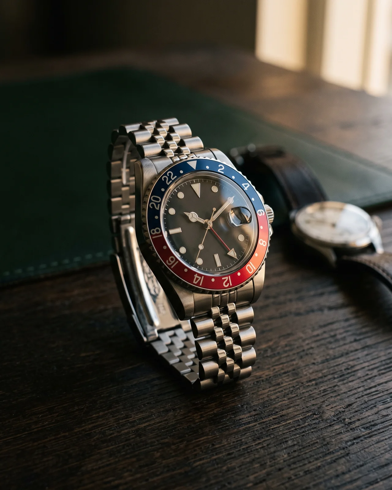 A steel Rolex GMT-Master II with a red and blue ceramic bezel on a Jubilee bracelet, bezel filling the frame, on a dark leather tray.