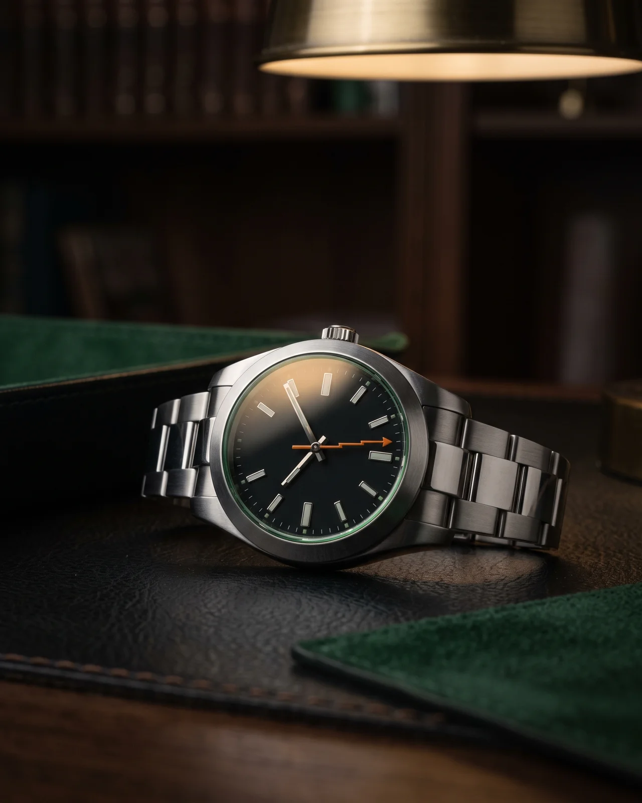 A steel Rolex Milgauss tilted under a brass lamp so the green edge of its sapphire crystal and the orange lightning-bolt seconds hand catch the light.