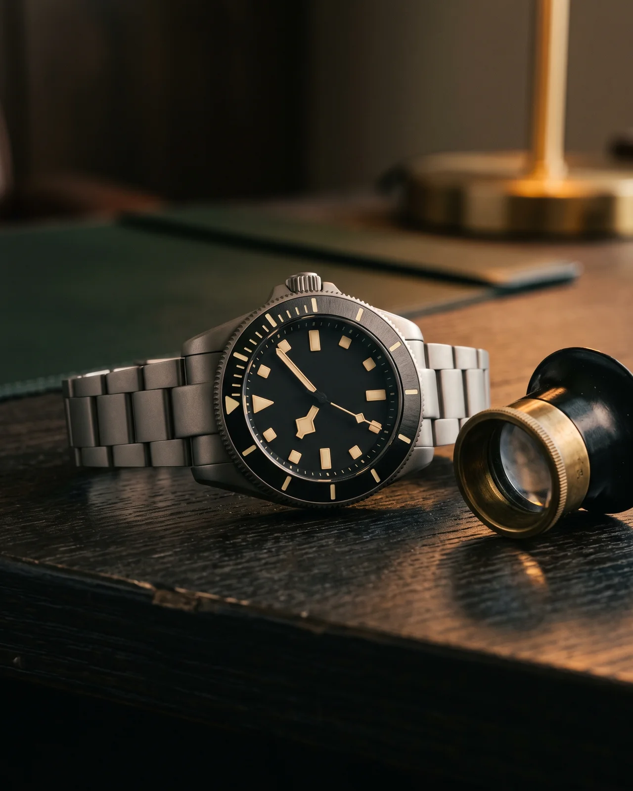 A titanium Tudor Pelagos clasp open on dark leather, the spring-loaded section and fold-out extension visible under a brass lamp.